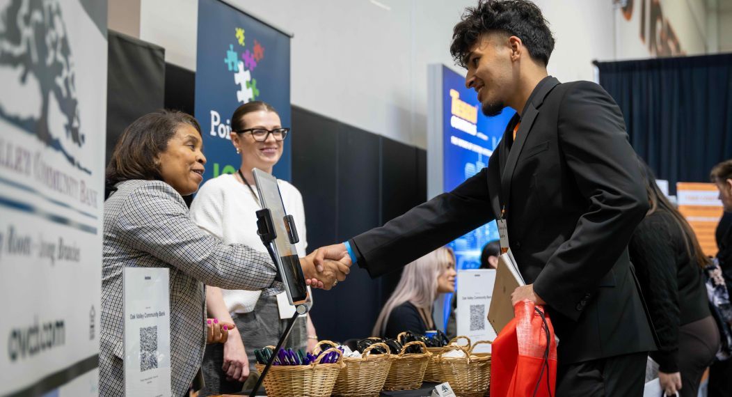 a student shakes the hand an an exhibit employer at a career fair